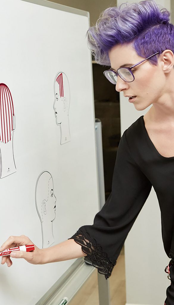 Pivot Point educator drawing sectioning at a whiteboard