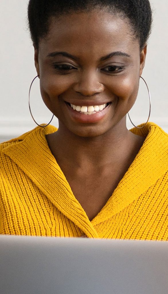 Young female wearing yellow sweater using a laptop.